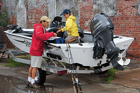 A father and son prepare equipment on their boat before going out to fish.