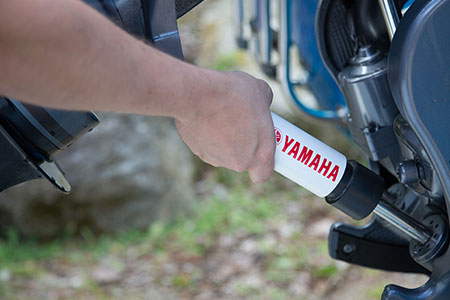 Someone installing a Yamaha engine support to hold the engine in the tilt-up position.