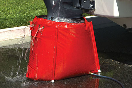 An outboard motor sits in a red flush bag filled with fresh water.