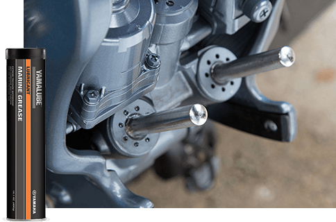 A close-up of the trim rams and seals on a Yamaha Outboard power trim and tilt unit with a bottle of Yamalube Marine Grease in the foreground.