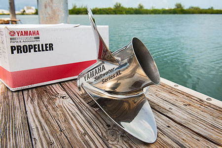 A Yamaha propeller sitting on a dock with the Yamaha box behind it.