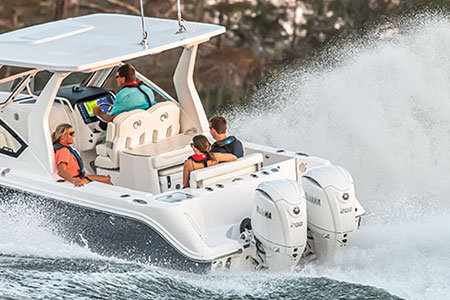 A man drives a Yamaha-powered boat while a woman and another couple enjoy the ride.